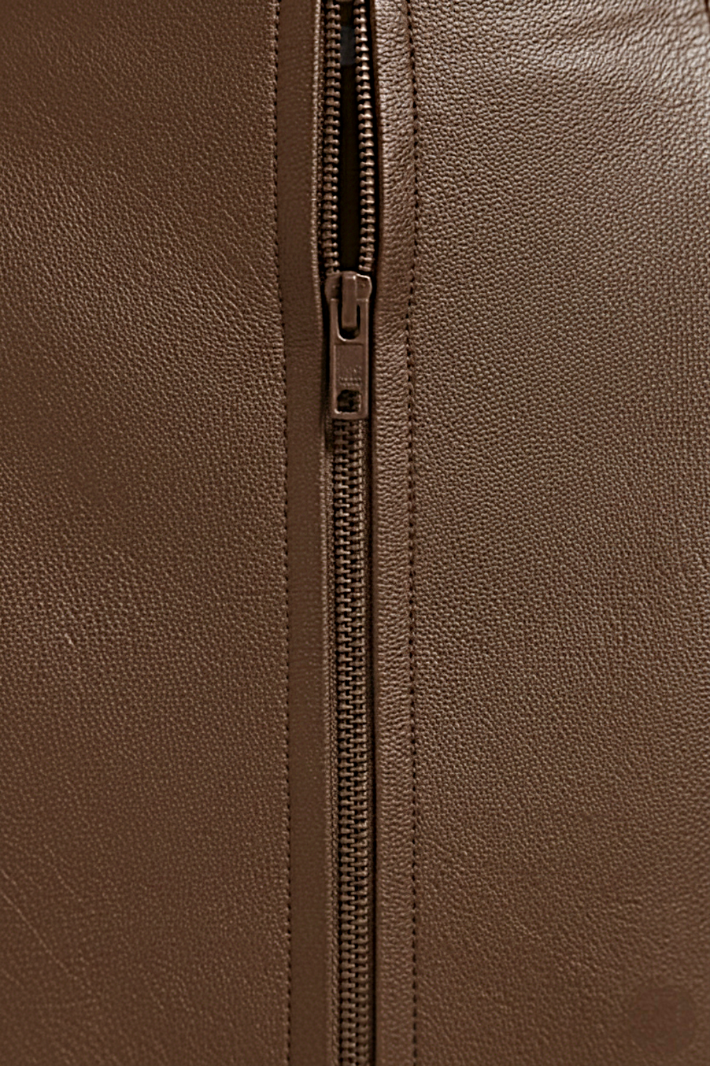 Macro shot of pebbled brown leather texture and discreet zipper closure on mini skirt. The Orla by Maverick Jacket.