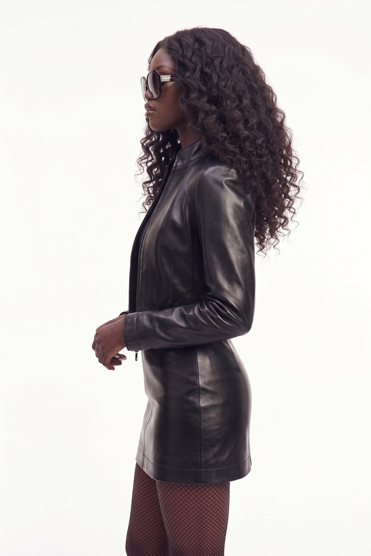 Side view of model in Maverick Tova cropped jacket, black tee, leather mini skirt and knee-high boots; short waist fit.