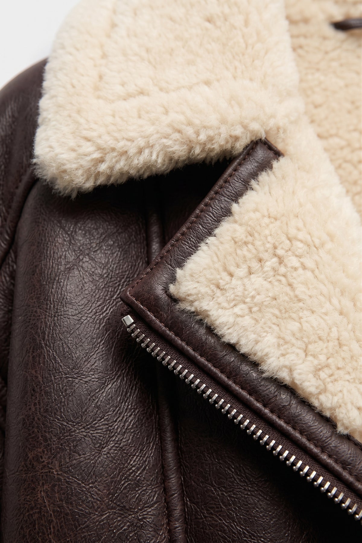 Detail of the Maverick Taryn B-3 shearling bomber jacket, highlighting distressed brown leather and cream shearling trim.
