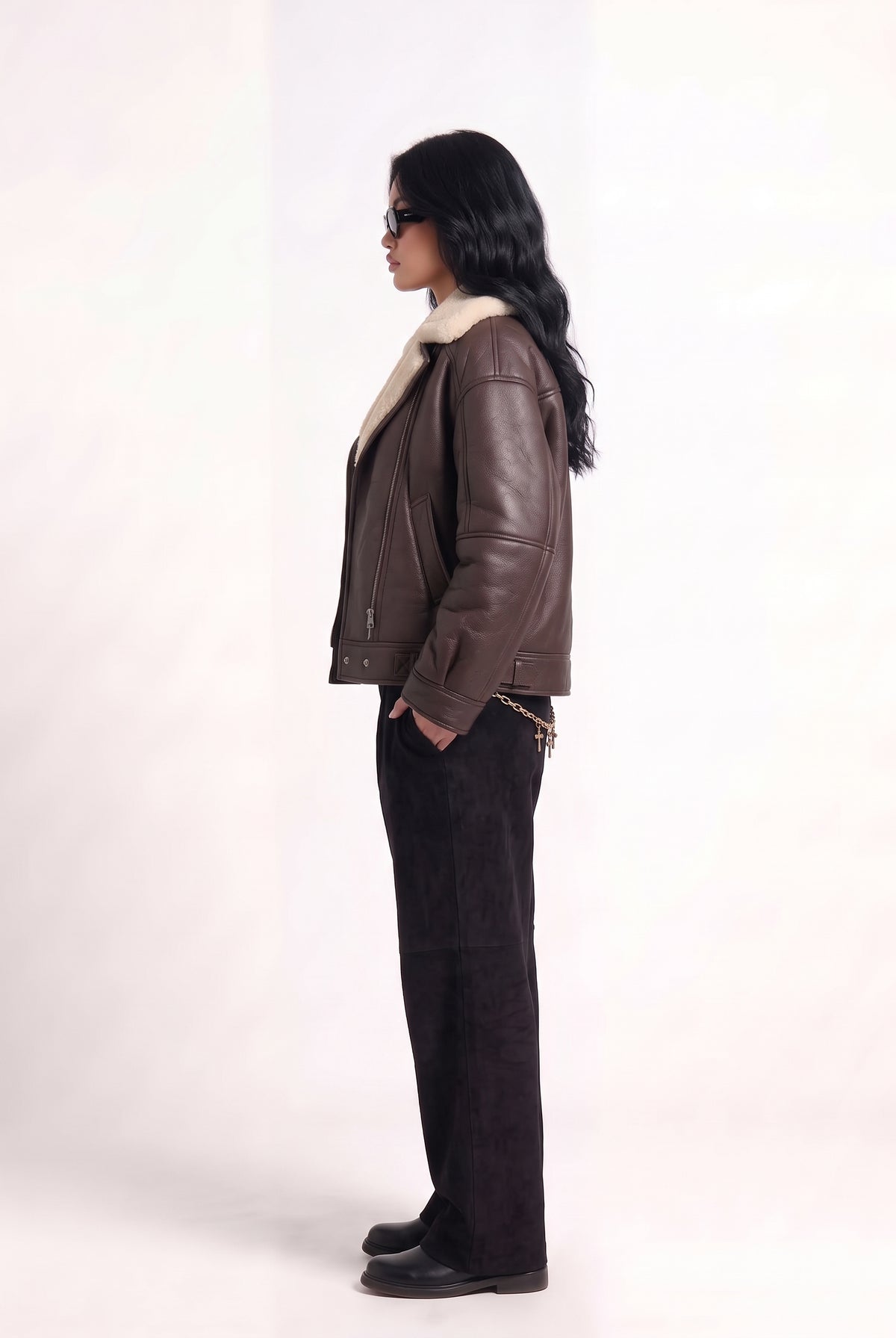 Side view of model in Maverick Taryn B-3 shearling bomber jacket, black tee, skinny black jeans and derby shoes; boxy fit.