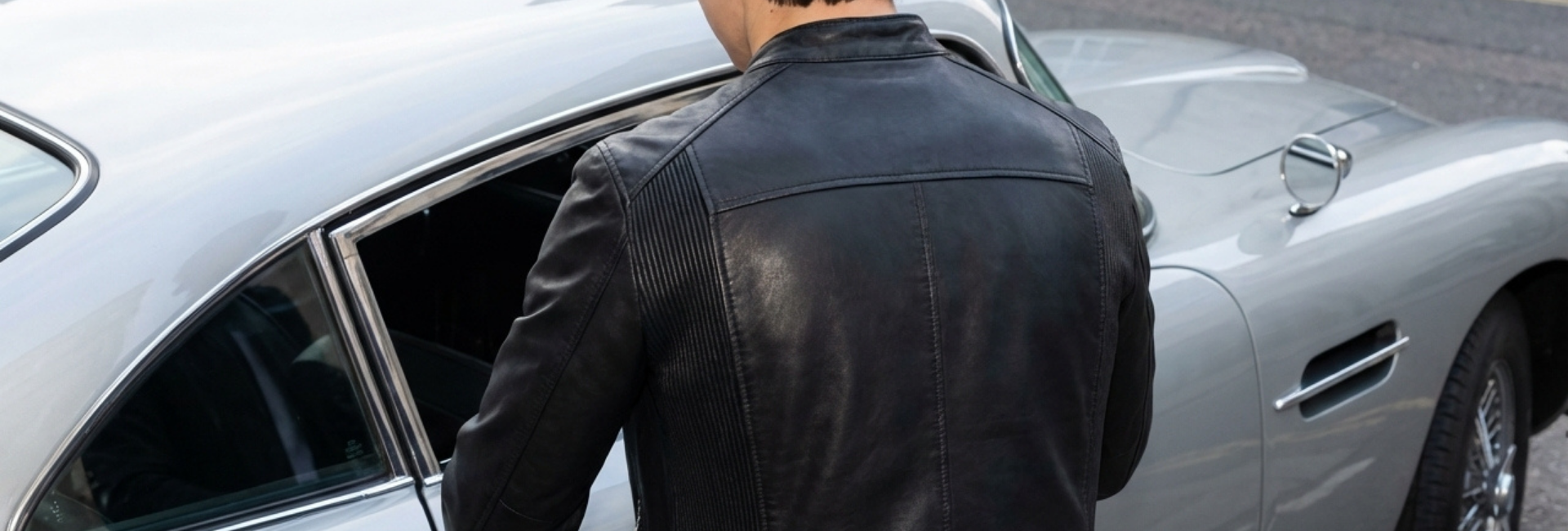 Person in a black leather jacket getting into a silver car